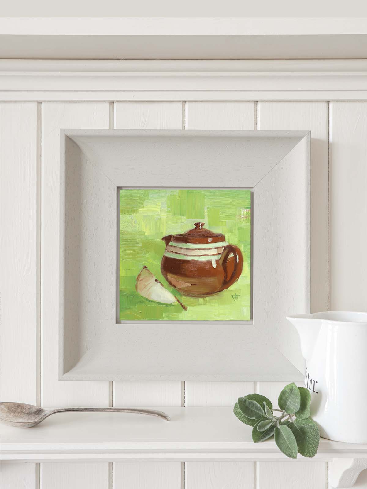 Vintage brown teapot painting in modern grey frame hanging on paneled kitchen wall