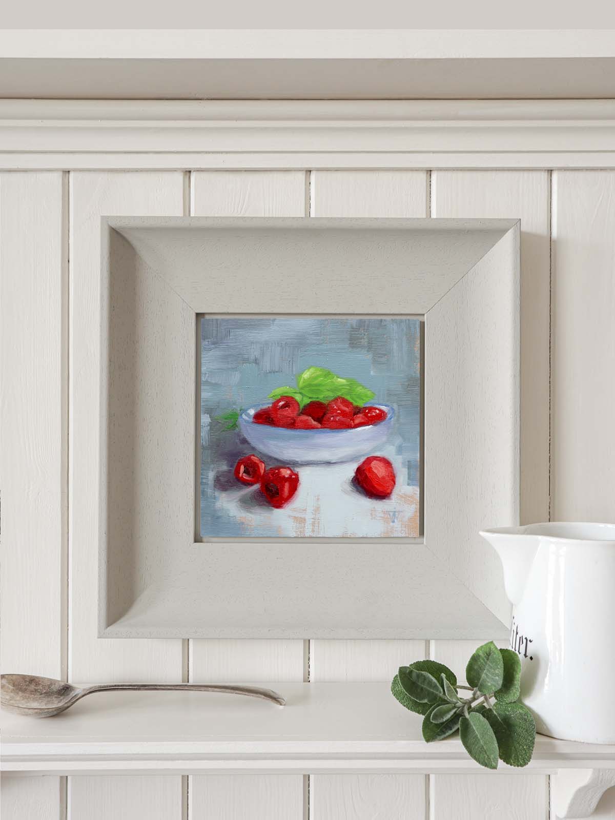 Small square raspberry painting in modern grey frame in contemporary kitchen setting.