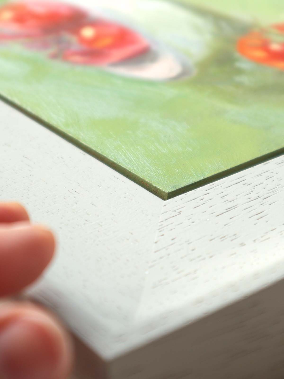Side angle of tomato painting in modern grey frame, showing close-up frame.