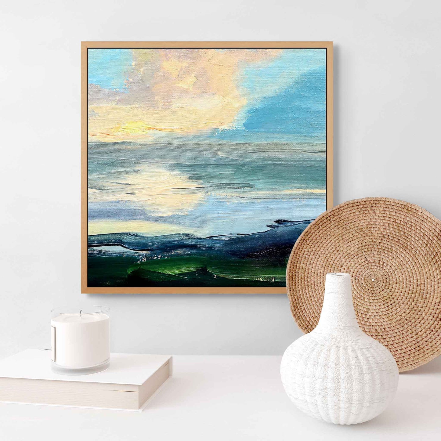 Framed abstract landscape painting on a white wall with decorative items below.