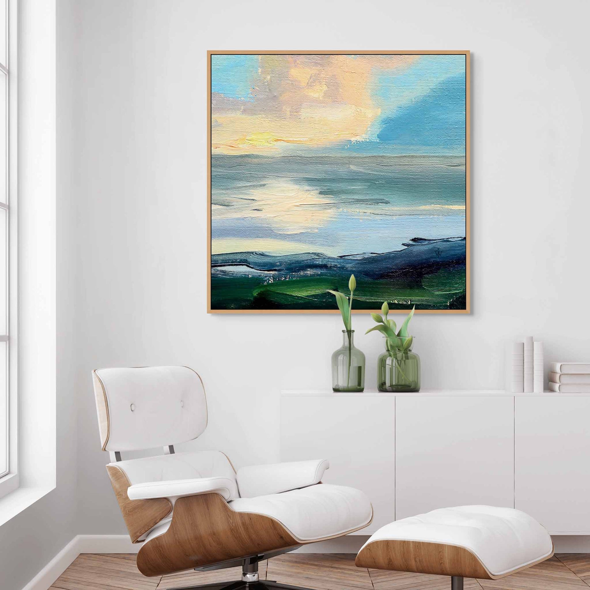 Peaceful canvas painting of dramatic clouds above the sea in a modern white living room interior.
