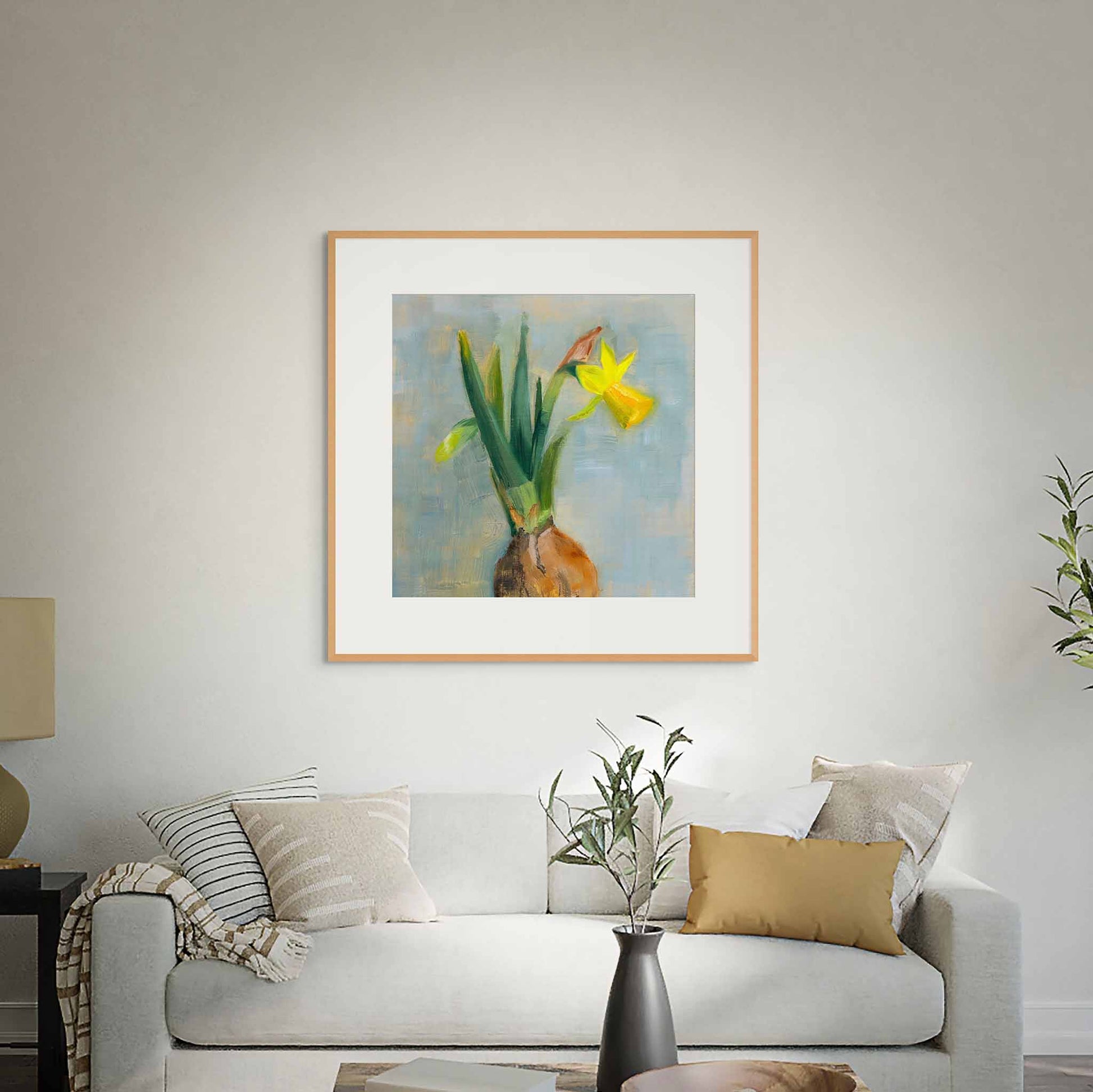 Framed artwork of yellow and green flowers above a sofa in a white living room