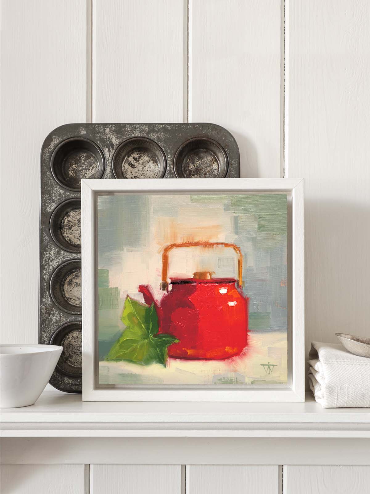 Red teapot with ivy painting in white tray frame displayed on kitchen shelf