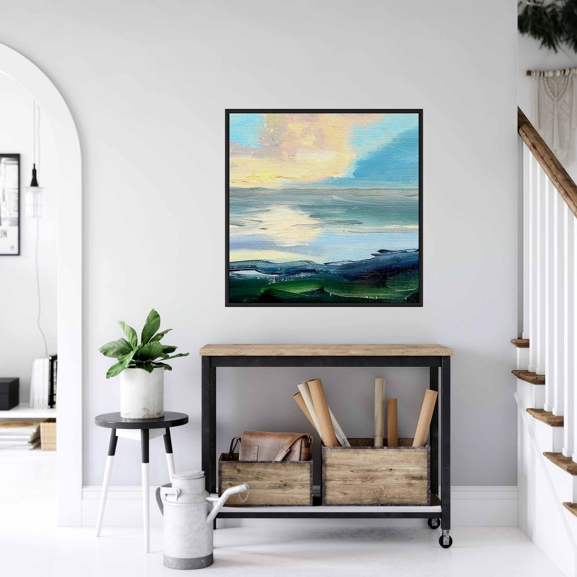 Navy blue and orange canvas art of sea and sky in floater frame hanging on a wall above a console table in a hallway.