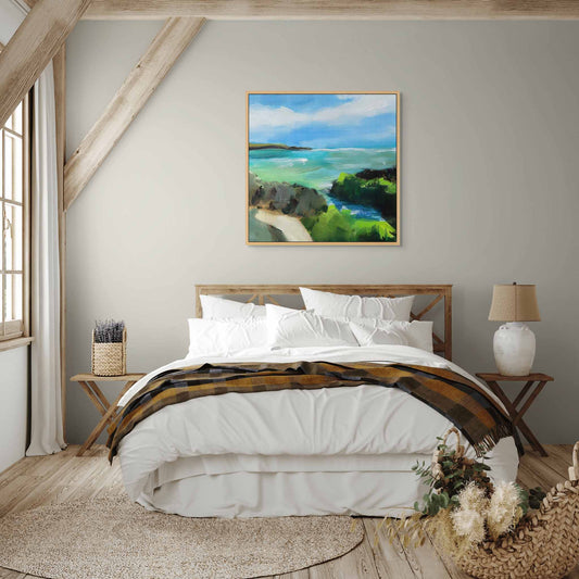Peaceful wall painting of turquoise sea and cliffs above wooden bed, in white and wood bedroom interior.