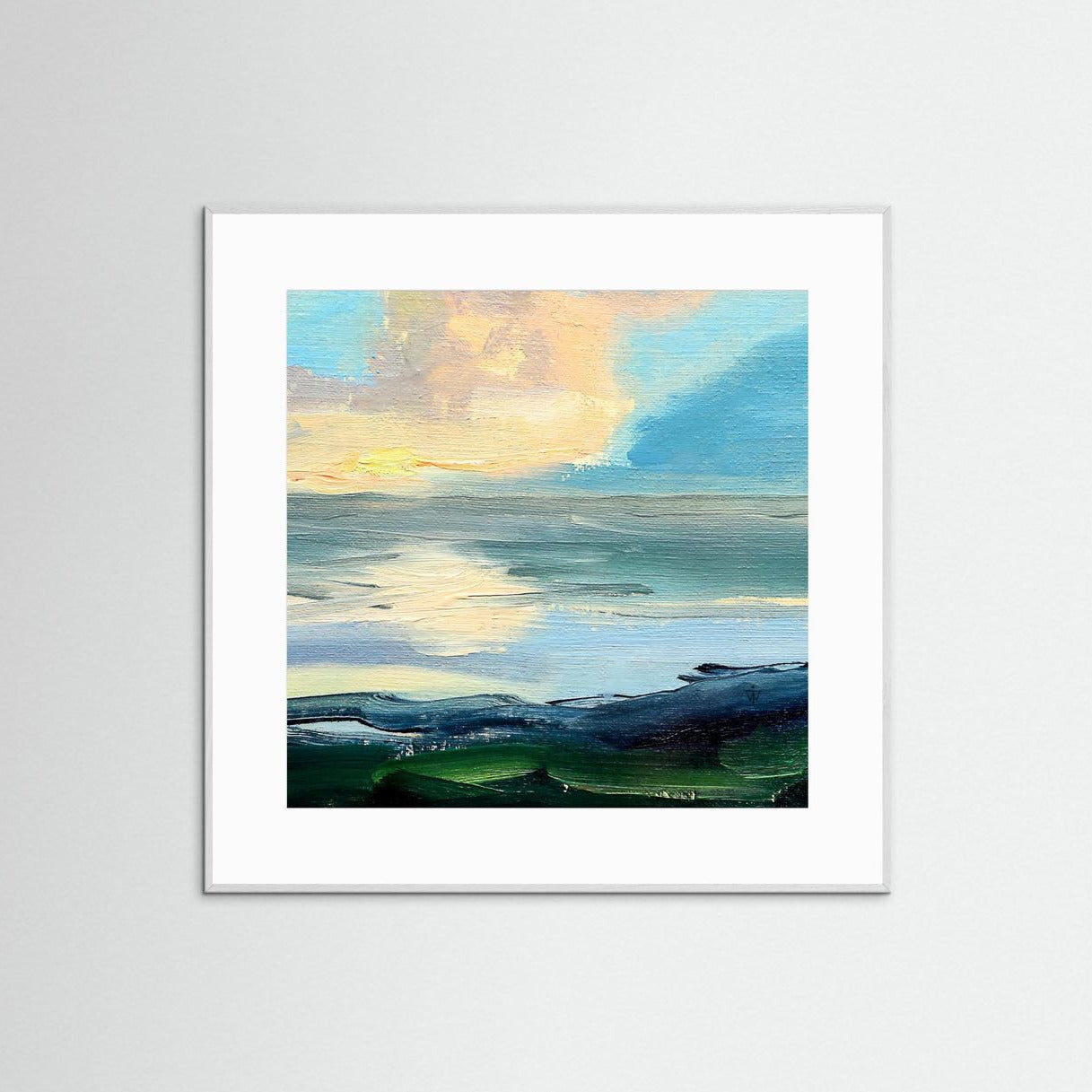 Framed artwork of a landscape with a blue sky and green rocks on a white wall.