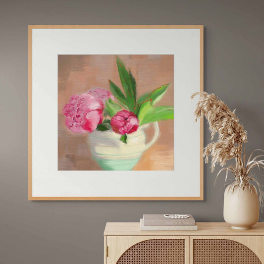 Pink peony fine art print in oak frame above wooden sideboard.