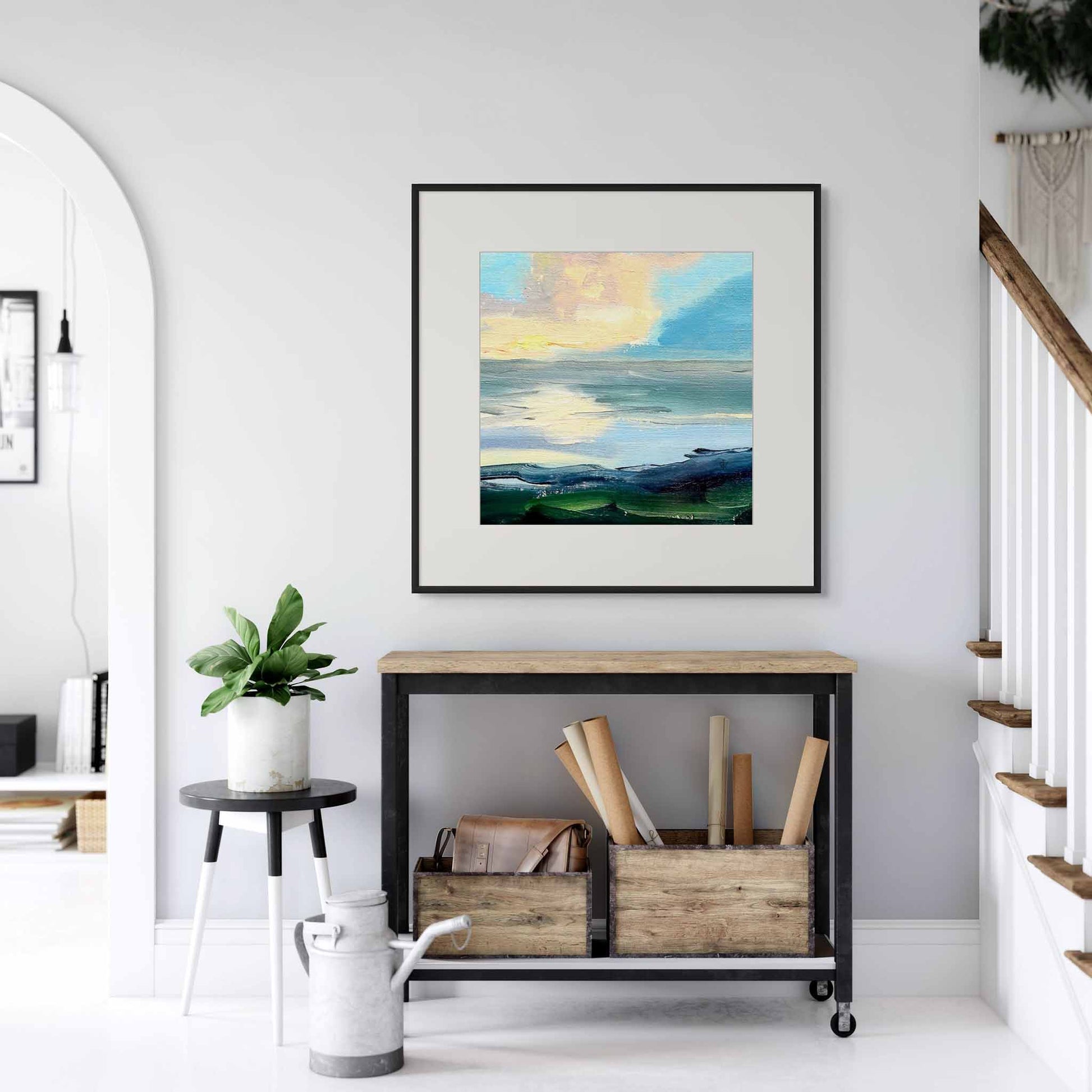 Framed artwork above a hallway table in a white entrance hall interior.