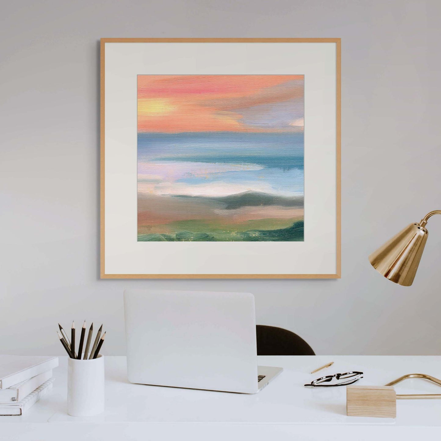 Framed artwork of a landscape with a sunset over a field in a home office setting.