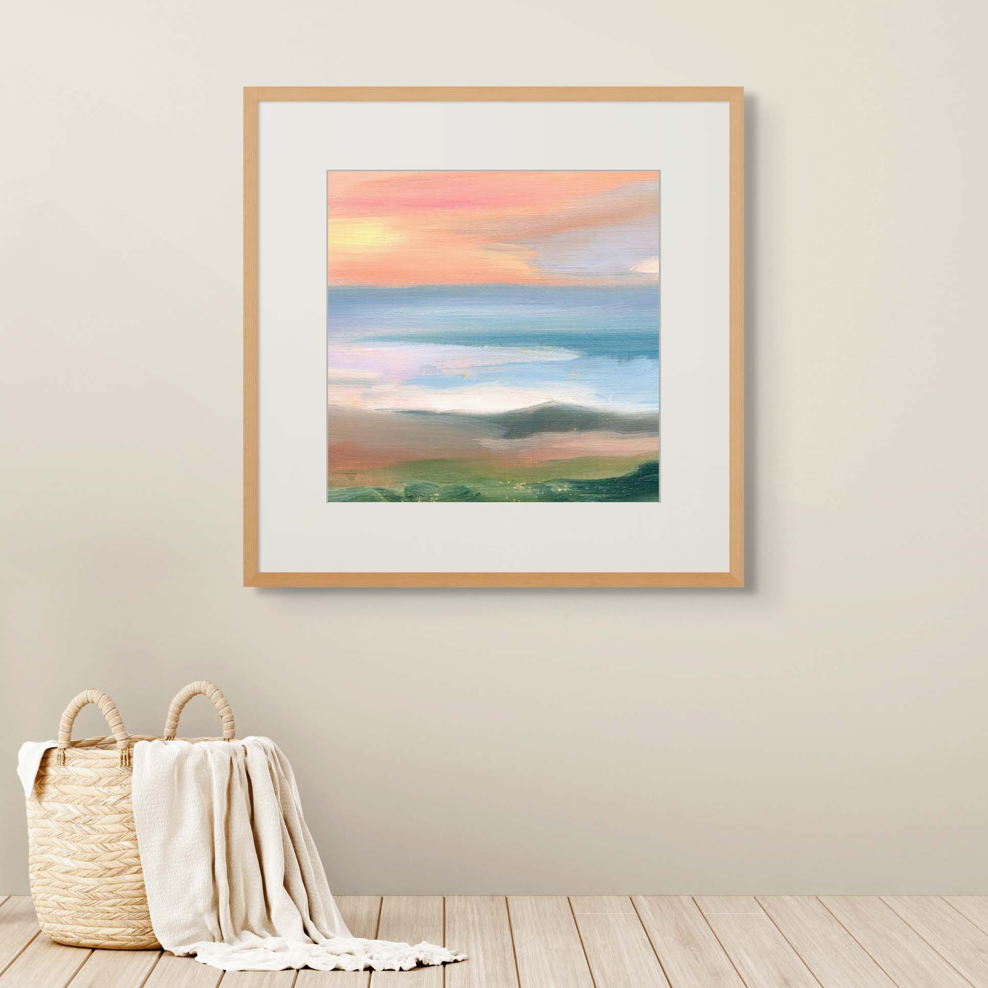 Framed landscape painting on a wall with a woven basket and blanket on the floor.