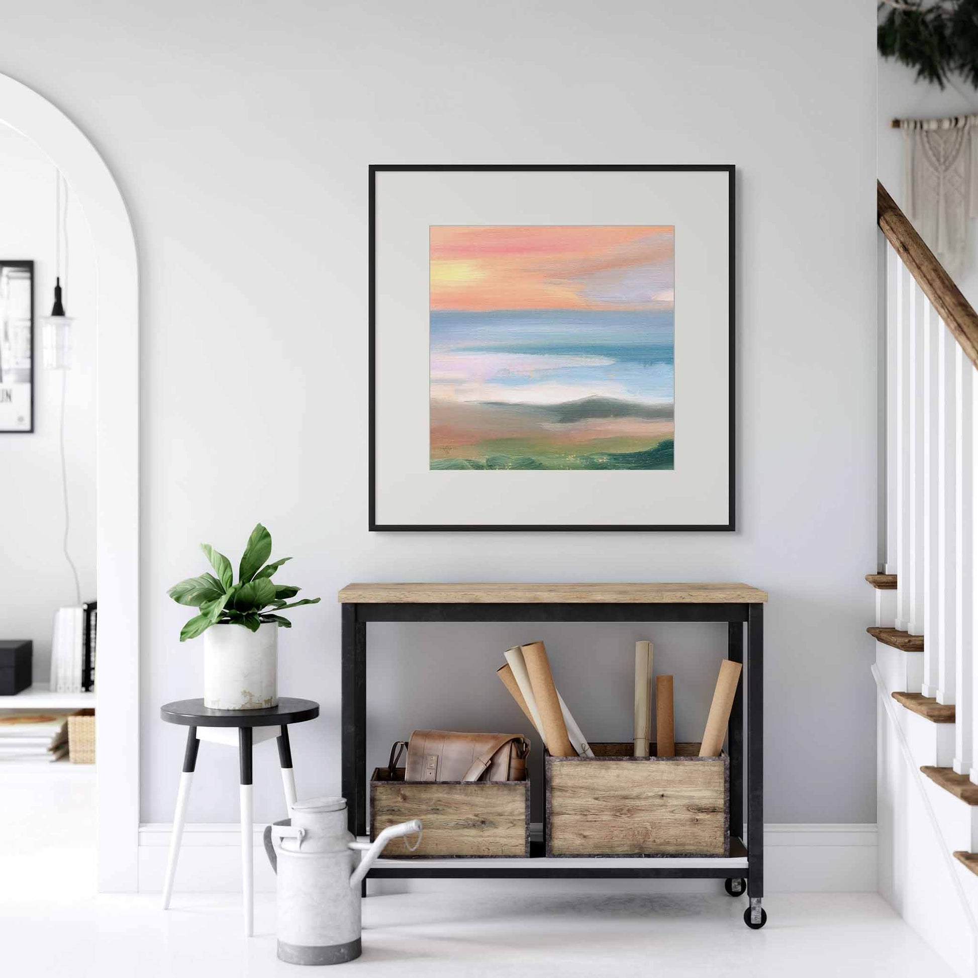 Framed artwork on a wall above a console table with decorative items in a white and airy home.